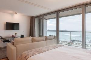 ein Schlafzimmer mit einem Bett und einem großen Fenster in der Unterkunft Bartolomeu Beach Apartments in Porto