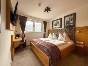 a bedroom with a bed and a desk and a window at Thurners Boutique Hotel at Großglockner, Film Inspired in Bruck an der Großglocknerstraße