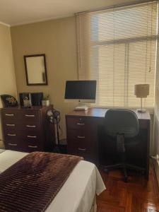 a bedroom with a desk with a computer and a bed at High Garden Apartment in Trujillo