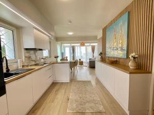 a kitchen with white cabinets and a large painting on the wall at Sunny Private Beach in Balatonlelle