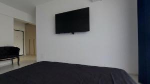 a bedroom with a bed and a flat screen tv on a wall at 85th Pool View Studio in Popeşti-Leordeni