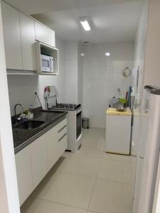 a white kitchen with a sink and a refrigerator at Paraiso dos coqueiros - Guarajuba - Bahia -Linha verde in Camaçari
