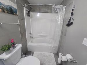 a white bathroom with a shower and a toilet at Comfortable Stay Evanston NW - Near YYC Airport, Highways, Shopping & Parks in Calgary +25 photos