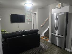 a black leather couch in a living room with a refrigerator at Comfortable Stay Evanston NW - Near YYC Airport, Highways, Shopping & Parks in Calgary
