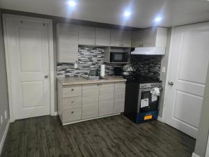 a kitchen with white cabinets and a black stove at Comfortable Stay Evanston NW - Near YYC Airport, Highways, Shopping & Parks in Calgary