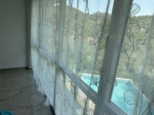 a window with a curtain with a view of a yard at guest house Qyteza in Shkodër