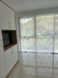 a living room with a large window and a kitchen at guest house Qyteza in Shkodër +1 photo