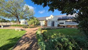 a white house with a bench in the yard at Midvaal Guesthouse in Meyerton