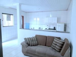 a couch in a living room with a kitchen at Ambiente familiar em Poços de caldas in Poços de Caldas