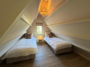two beds in a attic room with a window at Vakantiehuis Lucky in Ons Belang