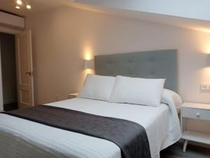 a bedroom with a bed with white sheets and pillows at Apartamentos Antuña in Cangas de Onís