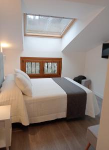 a bedroom with a large white bed with a window at Apartamentos Antuña in Cangas de Onís +6 photos