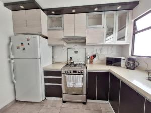 a kitchen with white cabinets and a stove and refrigerator at Habitación en departamento Compartido - La Paz 504 in Lima