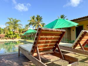two chairs and an umbrella next to a pool at Pousada Rancho Luar in Pôrto de Pedras
