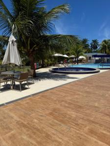 a patio with a table and an umbrella next to a pool at Paraiso dos coqueiros - Guarajuba - Bahia -Linha verde in Camaçari