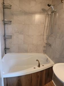 a bathroom with a tub with a shower and a sink at Alison A Romantic Getaway With Private Hot Tub in Rivière-Rouge +25 photos