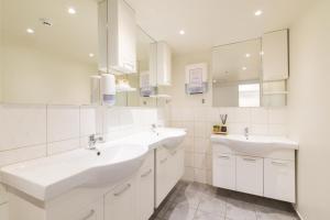 a white bathroom with two sinks and a mirror at Hostel Fjordur in Hafnarfjörður +28 photos