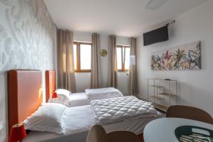 a bedroom with two beds and a tv on the wall at Foresteria SMART ROOMS in Viadana