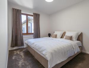 a white bedroom with a large bed and a window at The One Wadowice in Wadowice