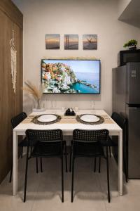 a kitchen with a white table with chairs and a tv on the wall at Casa MJ Suites at SMDC Fame Residences, Mandaluyong in Manila