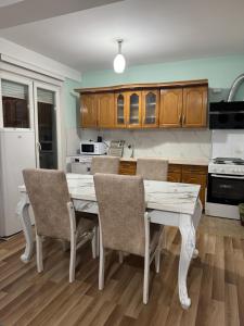 a kitchen with wooden cabinets and a white table and chairs at 2A Apartment in Prizren