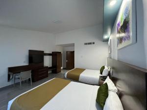 a hotel room with two beds and a desk at Solamar Inn Mazatlan in Mazatlán