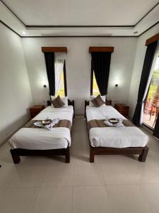 two beds in a room with two windows at Indra Yoga Retreat in Selemadeg