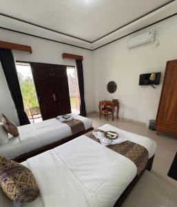 a room with three beds and a television in it at Indra Yoga Retreat in Selemadeg