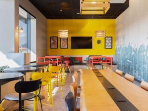a restaurant with tables and chairs and a yellow wall at ibis Styles Geneve Palexpo Aeroport in Geneva