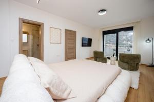 a white bedroom with a large bed and two chairs at Villa Azure Luxe in Škaljari