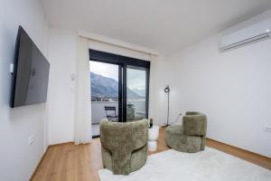 a living room with two chairs and a television at Villa Azure Luxe in Škaljari