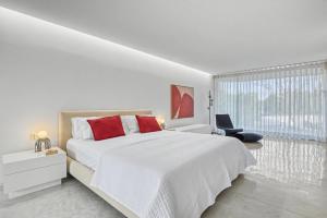 a white bedroom with a large bed with red pillows at Casa Torus Luxury Design Villa with Private SPA & Cinema in Jávea +69 photos
