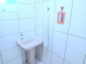 a white bathroom with a sink and a mirror at Casa simples e aconchegante em Poços de caldas in Poços de Caldas +15 photos