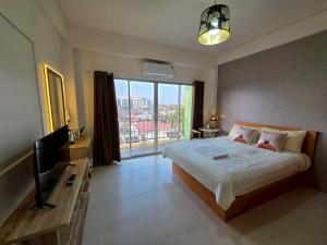 a bedroom with a bed and a television and a window at the stay bangsaen in Ban Rong Khoei