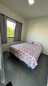 a bedroom with a bed with a floral bedspread and a window at Chácara Santa Fé in Iguatu +8 photos