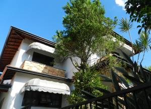 ein weißes Gebäude mit einem Baum davor in der Unterkunft Hospedaria Canto do Vinhedo in Espirito Santo Do Pinhal