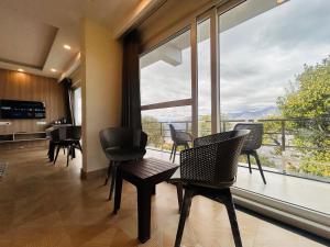a living room with chairs and a large window at The Hill Heaven A Luxury Property With Balcony & Mountain View Rooms in Mussoorie