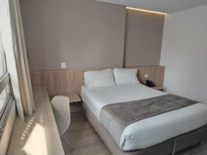 a bedroom with a large white bed and a window at ExpoStay Hotel Corferias Embajada Americana in Bogotá +63 photos