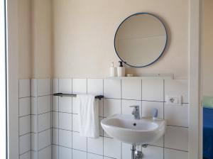 a white bathroom with a sink and a mirror at Petrikore - Rosso in Scoglitti