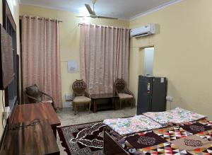 a room with two beds and a table and a refrigerator at Metro 21 in Faridabad