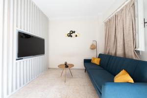 a living room with a blue couch and a tv at Mani Villa Ilias in Agios Nikolaos