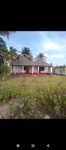 a house in a field with flowers in front of it at Demba Dou Suites Gardens in Batukunku