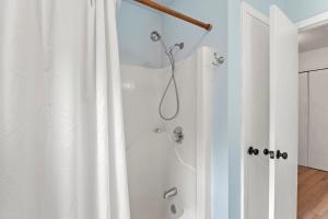 a shower with a white shower curtain in a bathroom at The Flying Dutchman OBX in Kill Devil Hills +18 photos