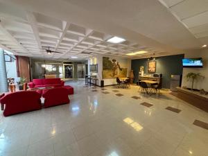 a large living room with red couches and a television at Hotel Enterprise Inn Plaza in León