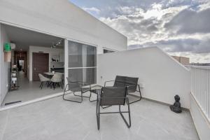 a patio with chairs and a table on a balcony at Top Floor Penthouse with Valletta Views & Terrace in Gwardamanġa