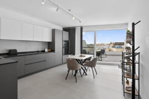 a kitchen with white cabinets and a table and chairs at Top Floor Penthouse with Valletta Views & Terrace in Gwardamanġa