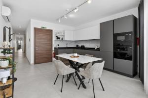 a kitchen with a white table and chairs at Top Floor Penthouse with Valletta Views & Terrace in Gwardamanġa