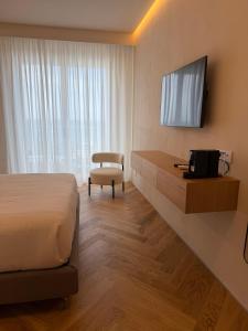 a hotel room with a bed and a desk with a television at Rumare - BADIA NUOVA in Trapani