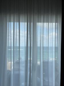 a window with white curtains with a view of the ocean at Rumare - BADIA NUOVA in Trapani