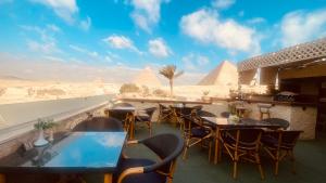 a view of the pyramids from a restaurant with tables and chairs at Seven Pyramids View Inn - Rooftop Breakfast in Cairo